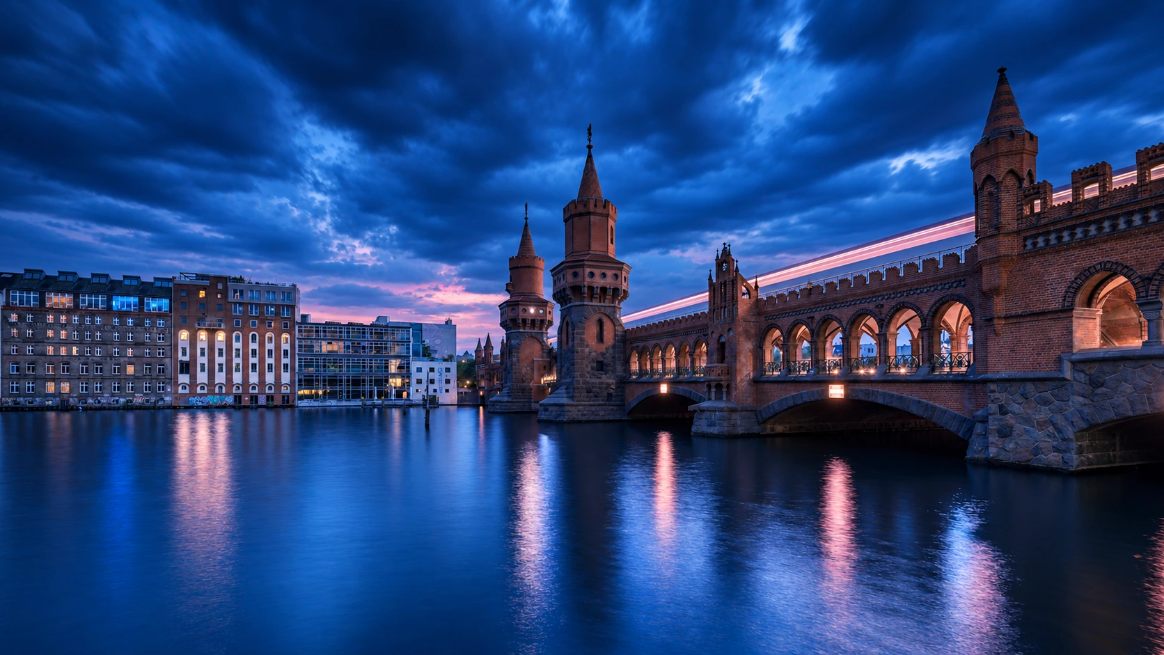 Berliner Oberbaumbrücke in Kobaltblau und Marineblau mit dezenten rosafarbenen Lichtreflexen auf der Spree